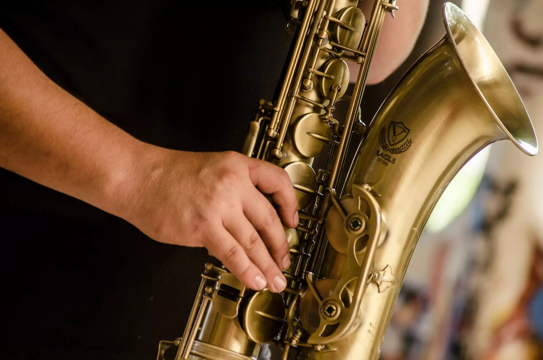 person in black shirt playing brass colored saxophone